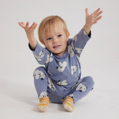 A blonde toddler wears matching top and bottom set in blue-gray color, it is covered with a pattern of friendly mice faces.