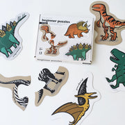 A box of dinosaur puzzles is shown with the put-together pieces surrounding it